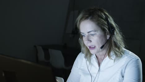 Woman-in-headset-working-in-dark-office